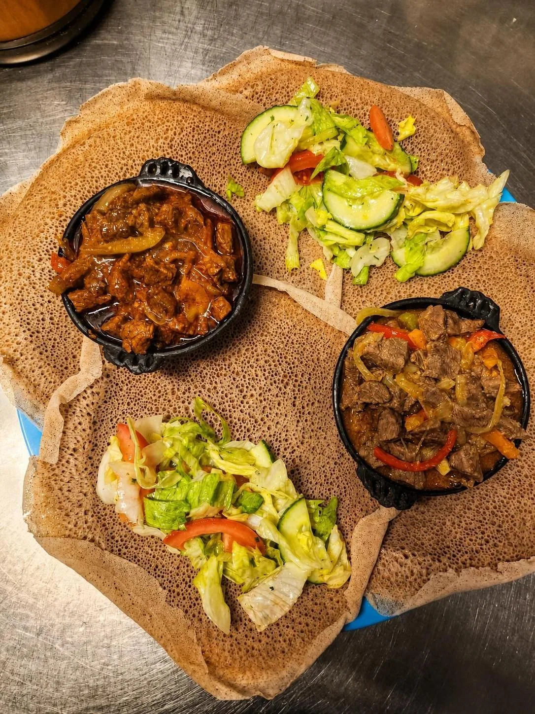 Injera mit Fleischgerichten und Salat von oben