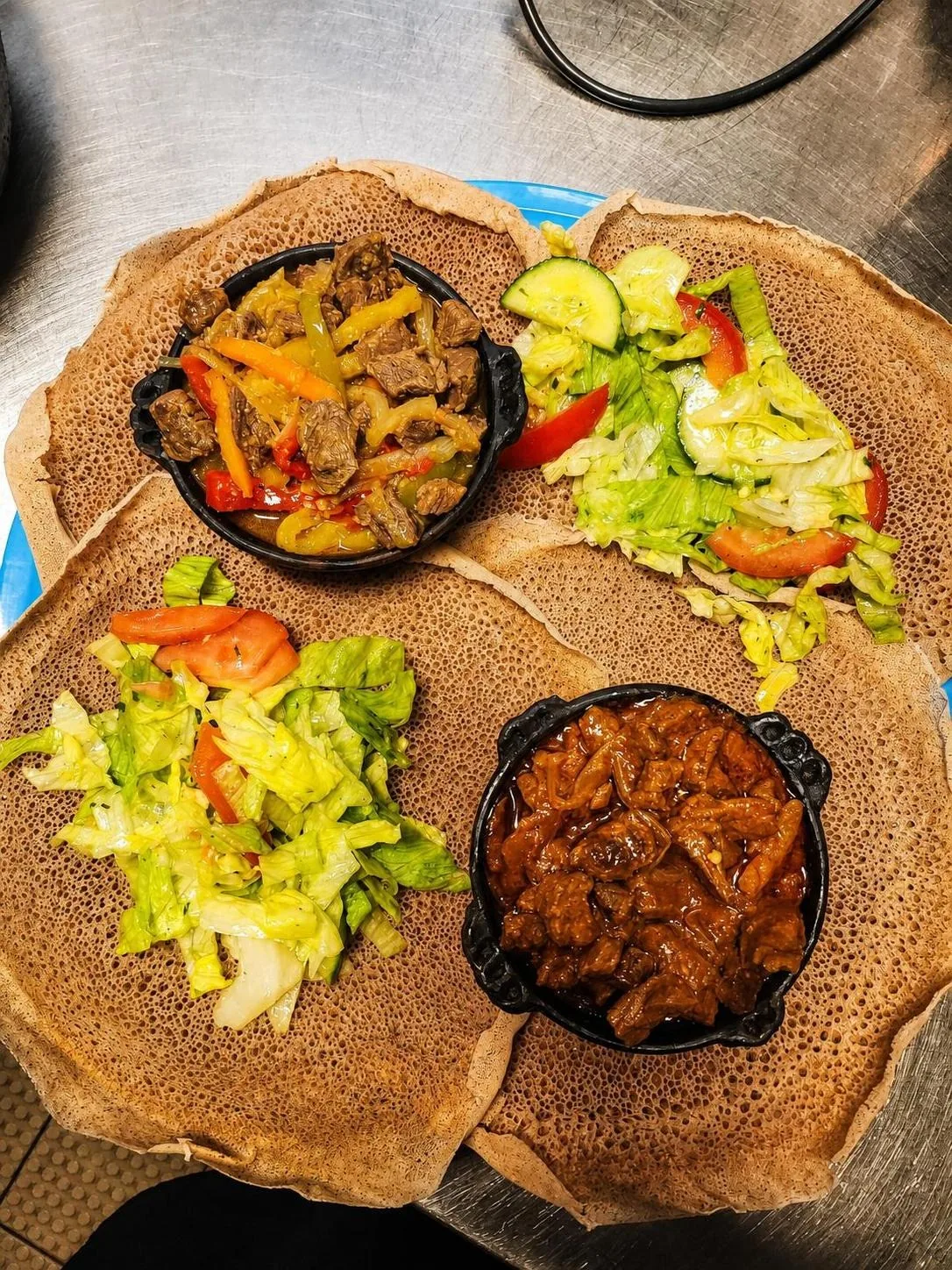 Injera mit zwei Fleischgerichten und Salat